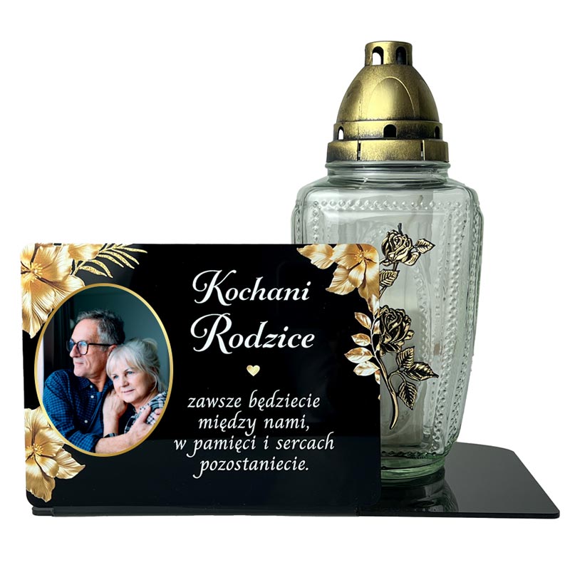 Statuetka ze Zdjęciem na Grób dla Rodziców MD1425. Personalizowana statuetka na grób z czarnej pleksi. Widoczne zdjęcie zmarłego, złote kwiaty i dedykacja, wykonane nadrukiem UV. Statuetka pełni funkcję podstawki na znicz. Pamiątka dla Mamy, Taty, Dziadka.
