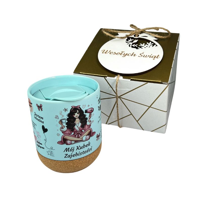 Świąteczny Gadżet dla Kobiety Kubek Zajebistości z Wieczkiem Zestaw MD1652. Mój Kubek Zajebistości, świąteczny zestaw prezentowy. Niebieski kubek 330 ml z korkowym spodem i drewnianym wieczkiem w ozdobnym pudełku z siankiem, obok biała ażurowa bombka z grawerem.