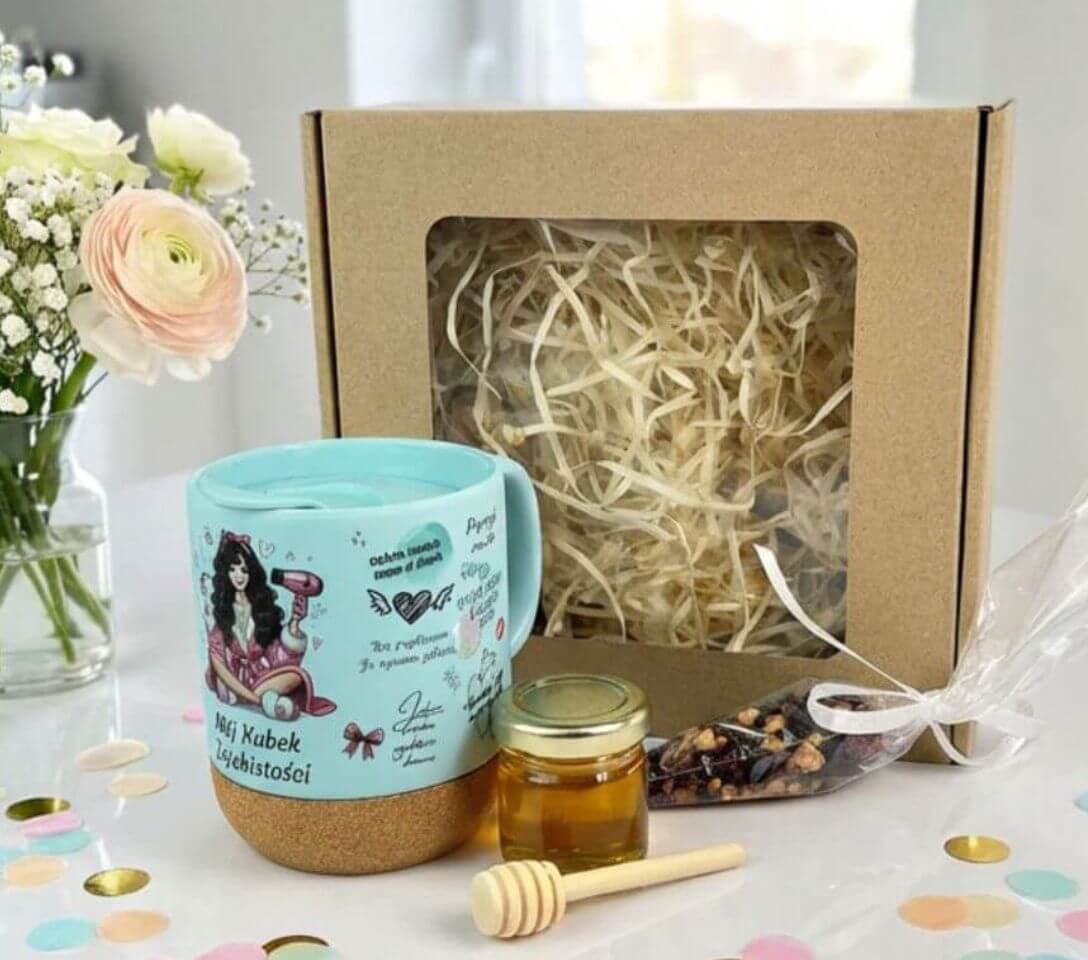 Zestaw prezentowy „Mój Kubek Zajebistości” – ceramiczny kubek z wieczkiem, owocowa herbata w rożku, miód z nabierakiem i dekoracyjne sianko w eleganckim pudełku.
