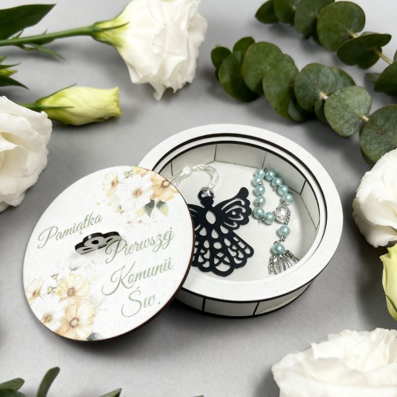 Białe okrągłe drewniane pudełko na pamiątkę Pierwszej Komunii Świętej z akwarelowym motywem żółtych kwiatów i ozdobnym napisem.