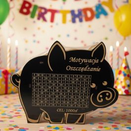 Drewniana skarbonka świnka z grawerowaną tabelą do wykreślania wpłat, cel oszczędnościowy 1000 zł, wykonana z naturalnej płyty HDF.