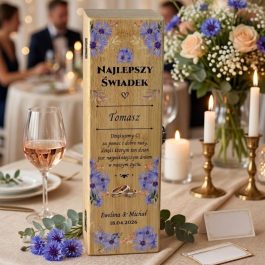 Podziękowanie dla świadka. Personalizowane bambusowe pudełko na wino dla świadka z nadrukiem fioletowych chabrów, złotych liści i połączonych obrączek. Widoczny polski tekst: NAJLEPSZY ŚWIADEK ♡ Tomasz, podziękowanie od pary młodej Ewelina & Michał, data 18.04.2026. Metalowe zawiasy i zapięcie widoczne z boku skrzynki.