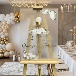 Akrylowa tablica powitalna na Pierwszą Komunię Świętą Gabrysi i Miłosza, wykonana z przezroczystej pleksi ze złotymi lustrzanymi napisami 3D i kolorowym nadrukiem UV z motywem kwiatów i kielicha.