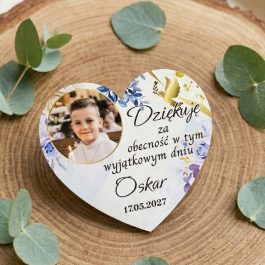 Personalizowana pamiątka komunijna w kształcie serca ze zdjęciem chłopca, niebiesko-fioletowymi kwiatami i złotym gołębiem na plasterku drewna z gałązkami eukaliptusa.