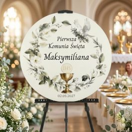 Tablica powitalna okrągła. pamiątka Pierwszej Komunii Świętej na czarnej mini sztaludze. Tabliczka ozdobiona jest akwarelowym wieńcem z zielonych gałązek i białych kwiatów, z gołębiem u góry. Centralnie umieszczony tekst w języku polskim: "Pierwsza Komunia Święta Maksymiliana". Pod tekstem widoczny złoty kielich z hostią z napisem "IHS" oraz data "02.05.2027".