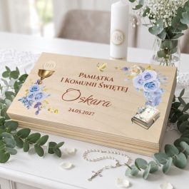 Pudełko na banknoty z magnesem z okazji Pierwszej Komunii Świętej dla dziewczynki i chłopca. Na wieku personalizowany nadruk w stylu akwareli przedstawiający niebieskie kwiaty piwoni, złoty kielich ihs i biblię. Widoczny napis: "Pamiątka I Komunii Świętej Pawła 24.05.2027". Produkt pokazany na białym tle w rzucie izometrycznym.