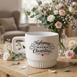 Kubek dla Matki Chrzestnej. Biały kubek ceramiczny z ozdobnym napisem Najlepsza Matka Chrzestna, kwadratowym uchem i ryflowaną podstawą na białym tle.
