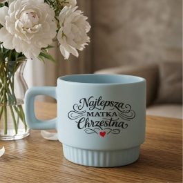 Prezent dla Chrzestnej . Błękitny kubek ceramiczny z ozdobnym napisem Najlepsza Matka Chrzestna, kwadratowym uchem i ryflowaną podstawą na białym tle.