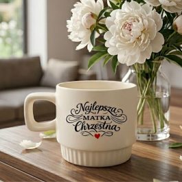 Podziękowanie dla chrzestnej. Kubek ceramiczny z ozdobnym napisem Najlepsza Matka Chrzestna, kwadratowym uchem i ryflowaną podstawą na białym tle.