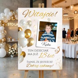 Spersonalizowana tablica powitalna na 18 urodziny Kuby ze zdjęciem i złotymi balonami, stojąca na drewnianej sztaludze w udekorowanej sali.